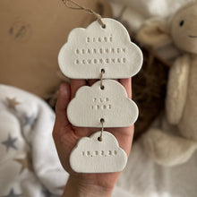 Load image into Gallery viewer, Three cloud-shaped tags with embossed text held in a hand, with a soft, blurred background.
